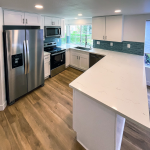 White Clairemont kitchen with L-shaped quartz peninsula, stainless French-door refrigerator, and blue tile backsplash