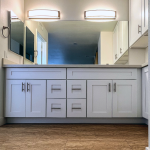 White shaker vanity with center drawer bank, wide mirror, and twin linear vanity lights in a La Mesa bathroom