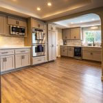 Undermount sink with matte black gooseneck faucet, white quartz countertop, and tile backsplash below a garden-view window