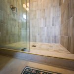 Walk-in shower with sliding glass door, vertical tile walls, and hexagon tile floor in a remodeled Santee bathroom