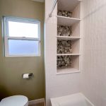 Recessed built-in shelves with mosaic tile backing next to a window and green painted wall