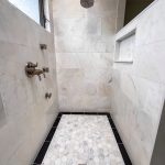 Marble hexagon mosaic shower floor with black tile border and a tall recessed wall niche