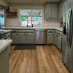 Remodeled College Area kitchen with sage green shaker cabinets, white subway tile, stainless refrigerator, and wood-look flooring